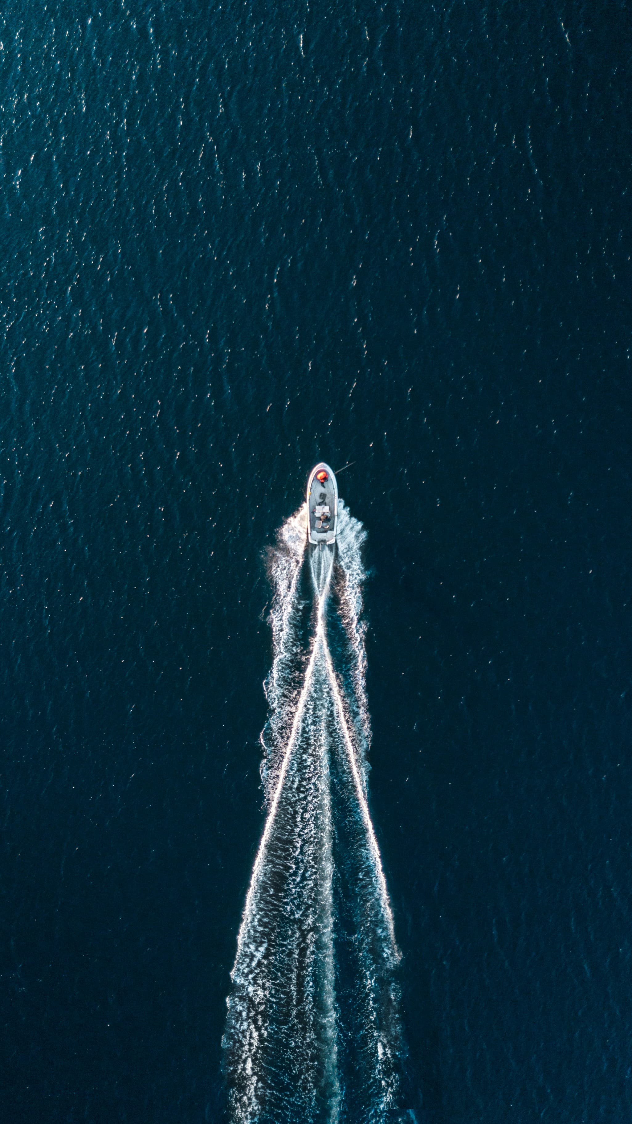 A boat crossing deep blue water from above